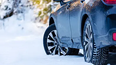 Das Bild zeigt einen Ausschnitt eines Autos von schäg hinten links, das in mehreren Zentimetern dickem Neuschnee parkt. - Foto: iStock/michalpalka