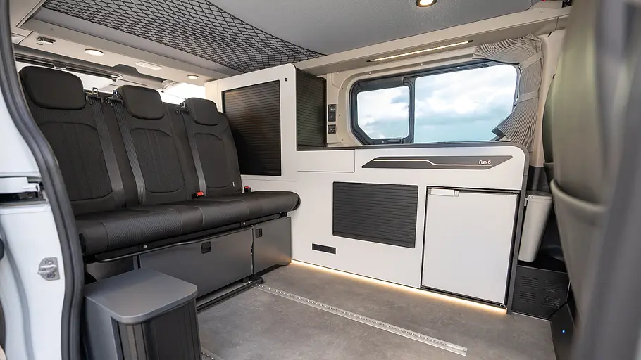 Blick durch die Schiebetüre in den Wohnraum des Antilope Van Flex 5 mit weißem Möbeldekor.