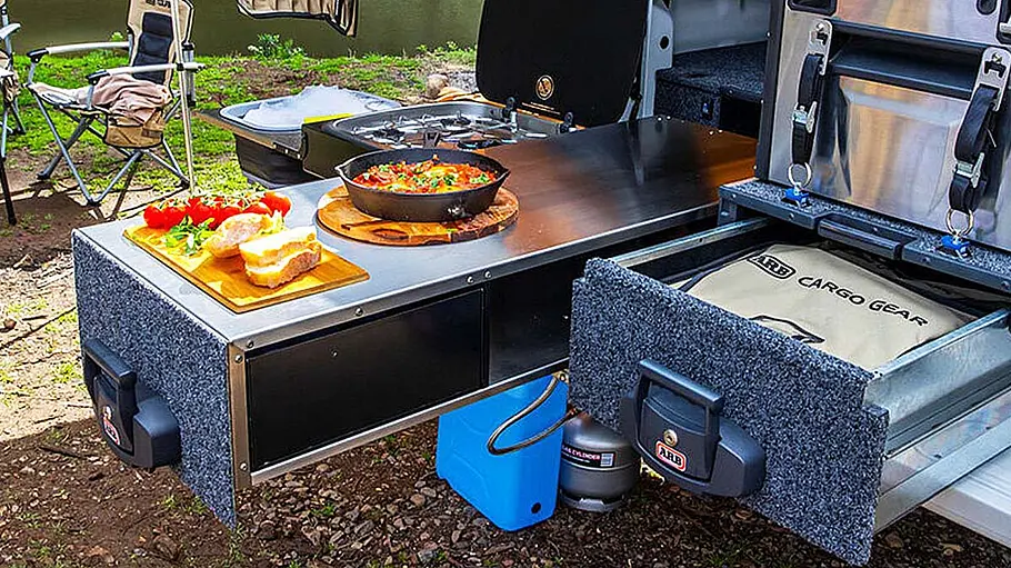Die ARB Slide Kitchen auf der Ladefläche eines Ford Ranger. Auf der Küche wird Essen zubereitet.