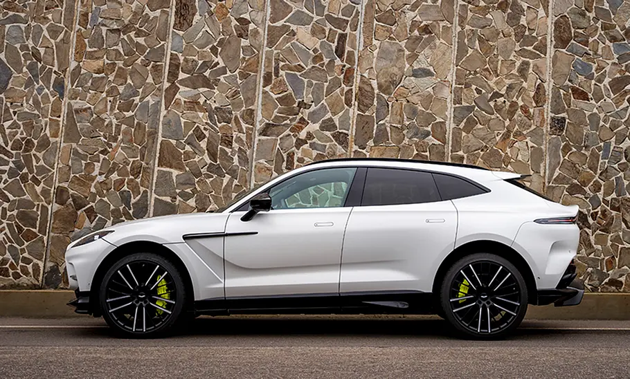 Der Aston Martin DBX in der Seitenansicht vor einer Wand.