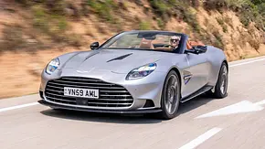 Der Aston Martin Vanquish Volante fahrend von schräg vorne mit offenem Verdeck. Redakteurin Adele Moser am Steuer. - Foto: Aston Martin