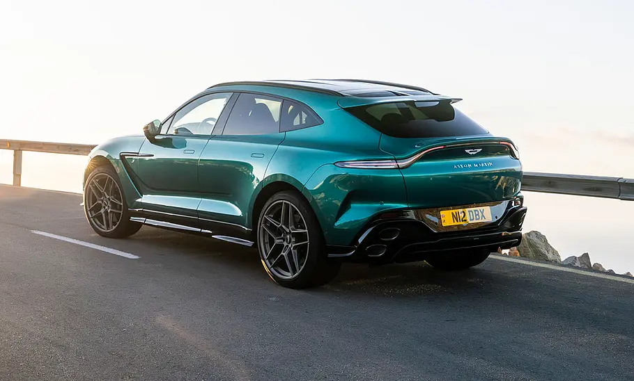 Der Aston Martin DBX S (2025) fahrend auf einer Straße in der Seitenansicht.