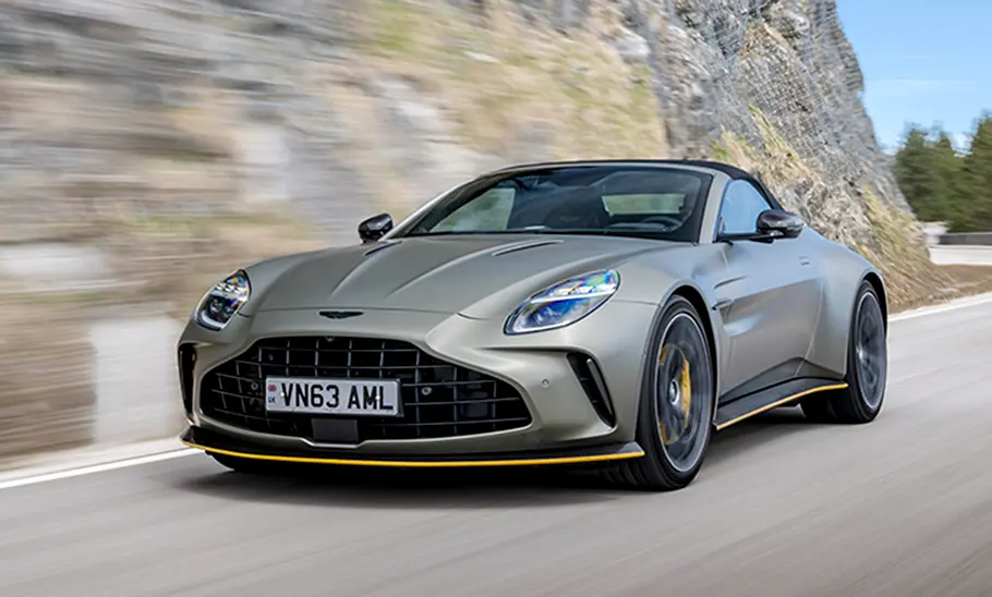 Der Aston Martin Vantage Roadster (2025) fahren auf einer Straße von seitlich vorne.