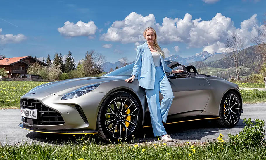 Der Aston Martin Vantage Roadster (2025) stehend auf einer Straße von der Seite mit Redakteurin Adele Moser.