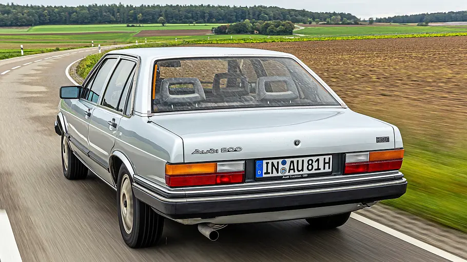 Audi 200 5T fahrend von schräg hinten fotografiert. 