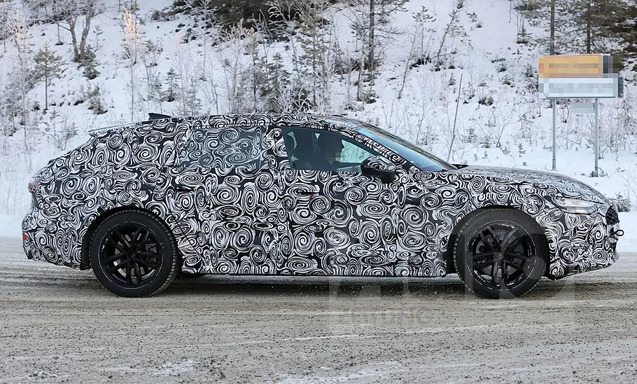 Der Audi A6 Allroad (2025) als Erlkönig fährt durch eine Kurve, von der Seite fotografiert.