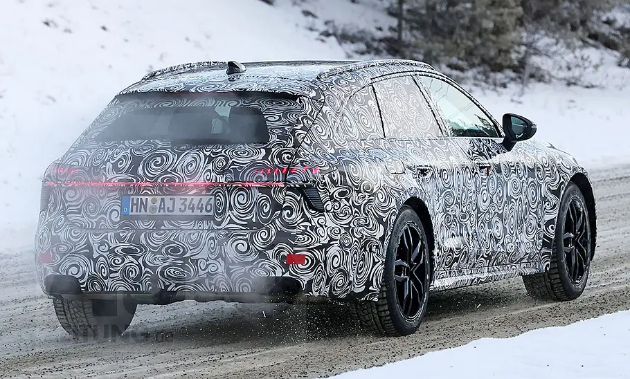 Der Audi A6 Allroad (2025) als Erlkönig fährt durch eine Kurve, von schräg hinten fotografiert.