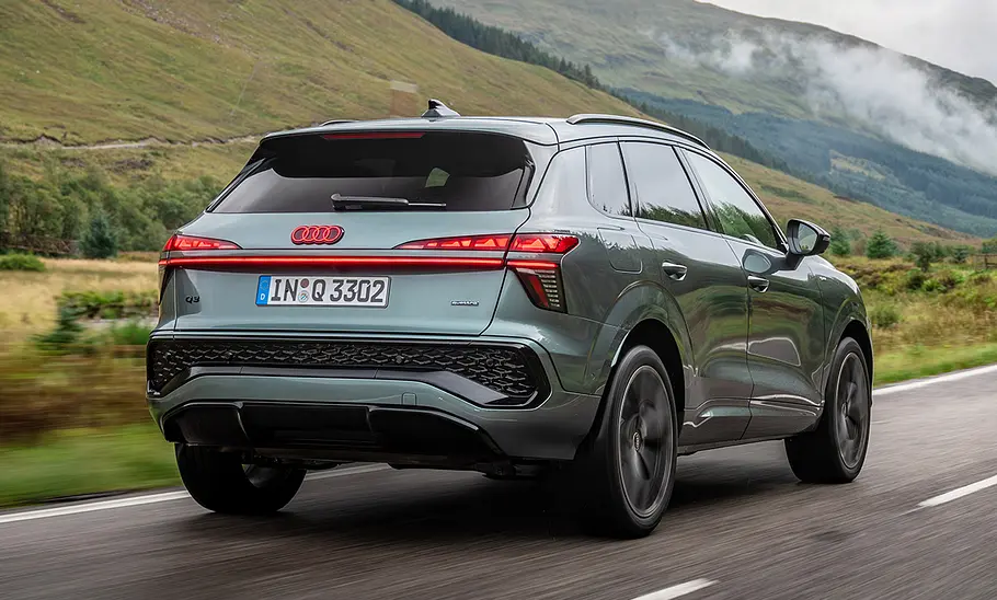 Der Audi Q3 (2025) fahrend auf einer Straße in der Ansicht von schräg hinten.