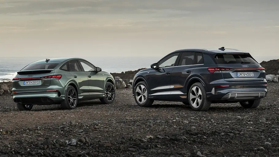 Audi Q4 e-tron Facelift Der Audi Q4 e-tron steht als SUV und Sportback an einem Geröllstrand, von hinten fotografiert.