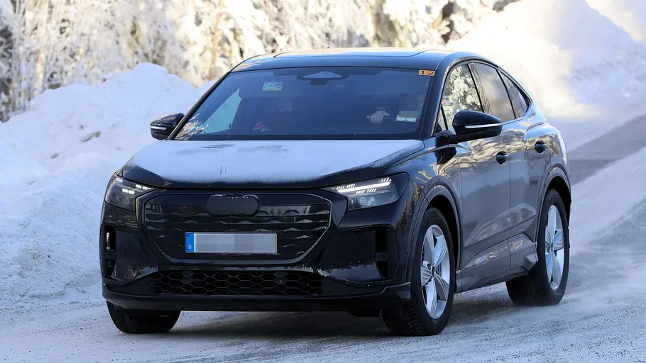 Der Audi Q4 Sportback e-tron fährt als Erlkönig auf einer verschneiten Straße, von vorne fotografiert.