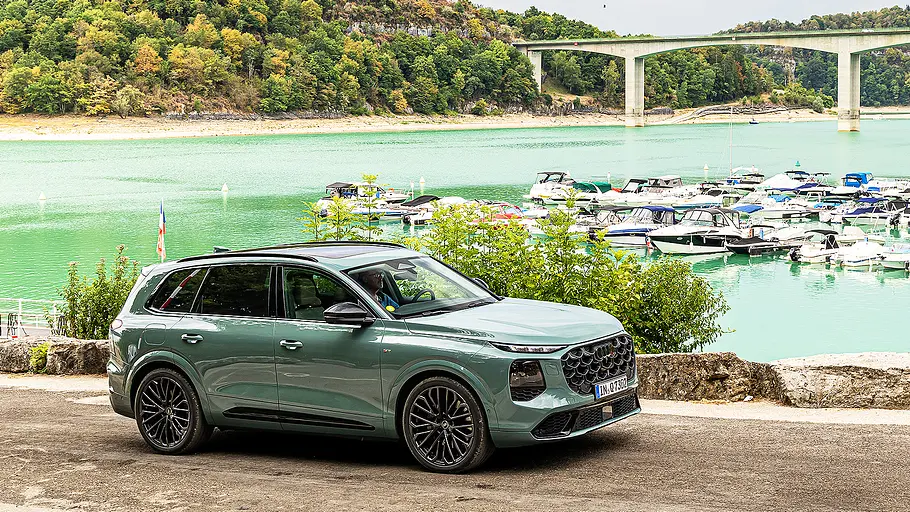 Audi Q7 (2026) Blick von schräg vorne auf den Audi Q7 (2026) vor einer Hafenlandschaft.
