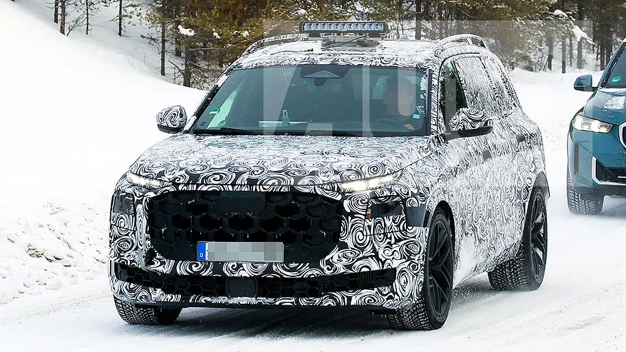 Audi Q9 (2026) Blick von schräg vorne auf den fahrenden Erlkönig des Audi SQ9 (2026).