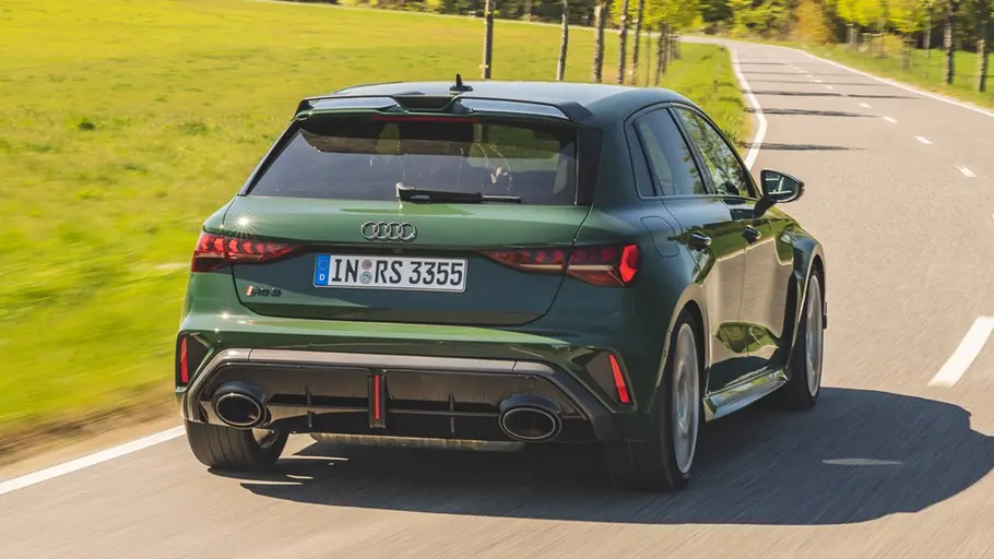 Der Audi RS 3 Competition Limited fahrend von schräg hinten rechts auf einer Landstraße.