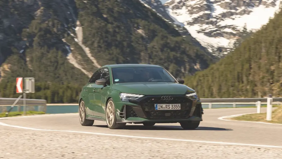 Der Audi RS 3 Competition Limited fährt durch eine Linkskurve, im Hintergrund sind ein See und Berge zu sehen.