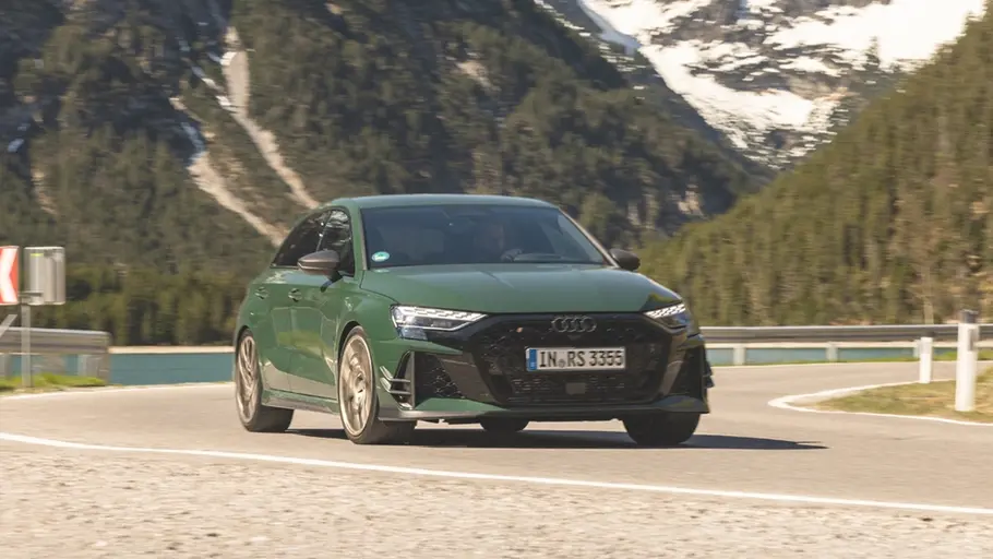 Der Audi RS 3 Competition Limited fährt durch eine Linkskurve, im Hintergrund sind ein See und Berge zu sehen.