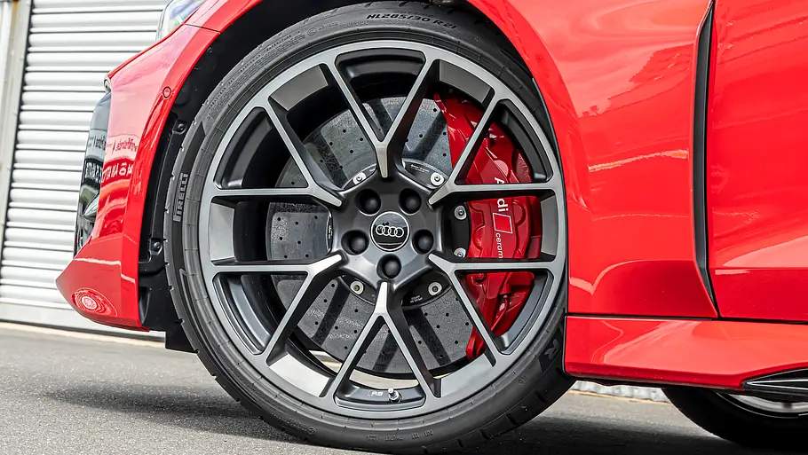 Audi RS 5 Avant Tracktest Das Vorderrad des roten Audi RS 5 Avant mit dunkler Mehrspeichenfelge, gelochter Bremsscheibe und rotem Bremssattel ist zu sehen.