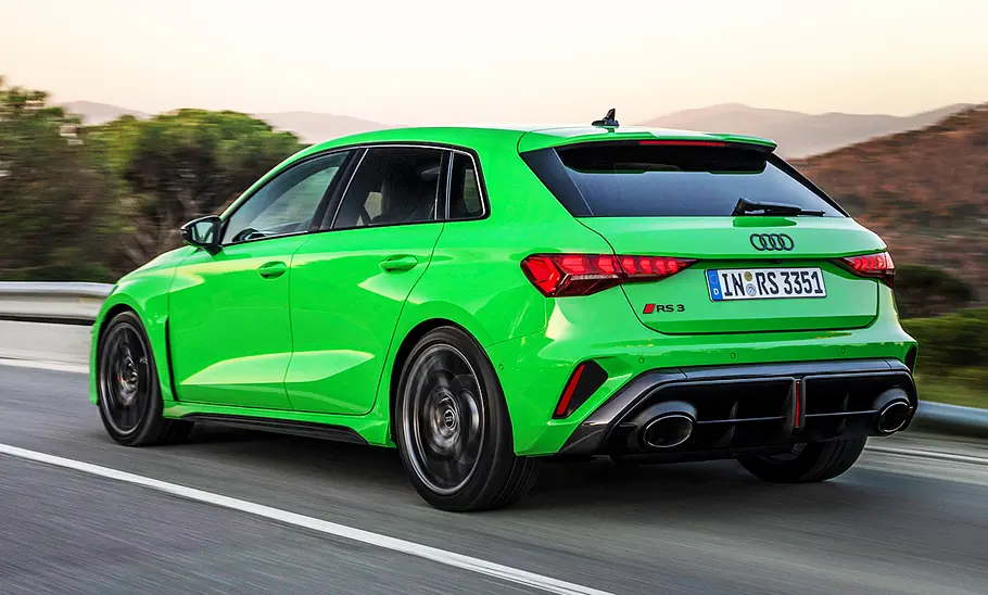 Das Audi RS 3 Sportback Facelift (2024) fährt über die Landstraße, von schräg hinten fotografiert.