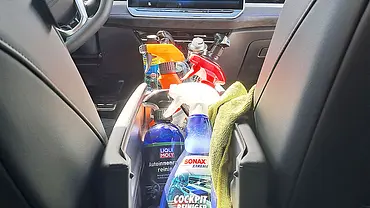 Sprühflaschen mit Cockpitspray und ein Lappen stehen und liegen in der Mittelkonsole eines Testwagens. - Foto: AUTO ZEITUNG