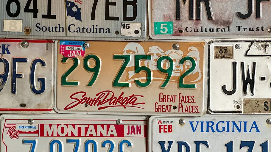 Wahrheit über Autokennzeichen Verschiedene us-amerikanische Autokennzeichen an einer Wand montiert.