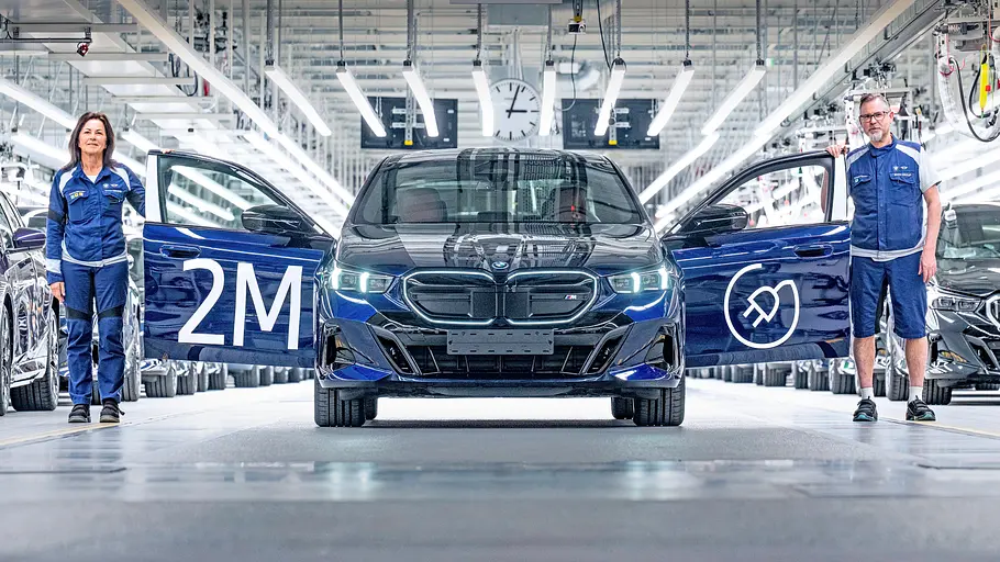 Die Produktion eines BMW i5 in einer Halle von vorne fotografiert.
