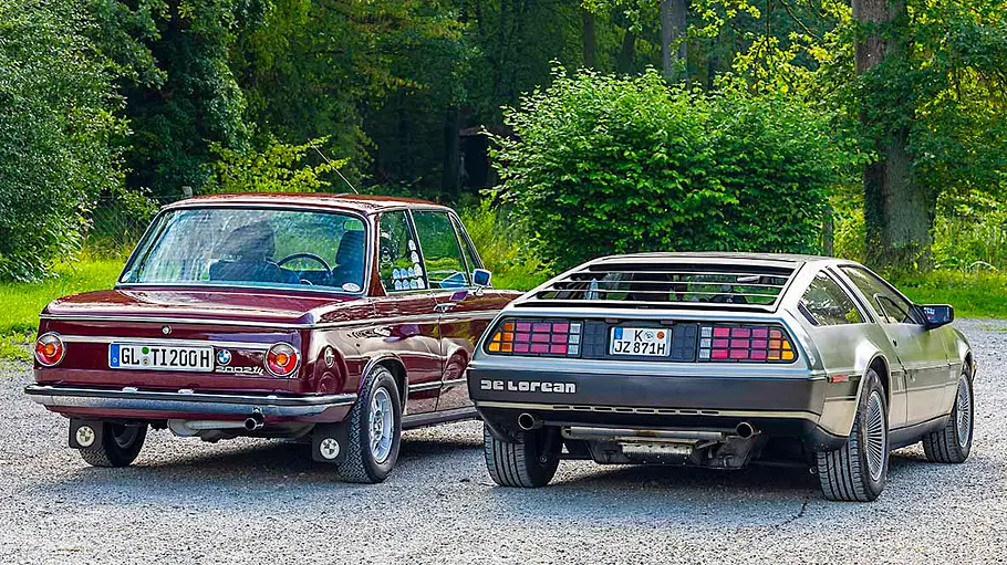 BMW 2002 tii/DeLorean DMC-12 Heckansicht stehend.
