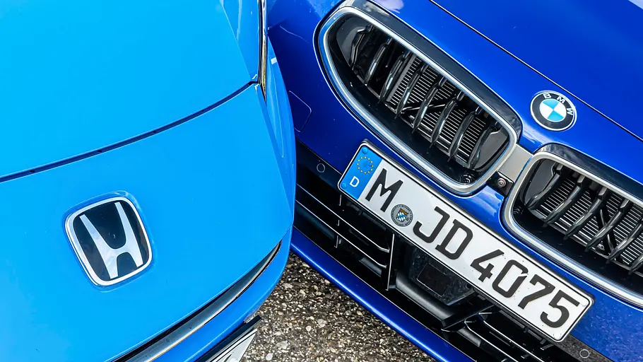 BMW 2er Coupé gegen Honda Prelude im Vergleichstest Die Fronten eines hellblauen Honda Prelude und eines dunkelblauen BMW 2er Coupé stehen dicht beieinander, mit sichtbaren Markenlogos.