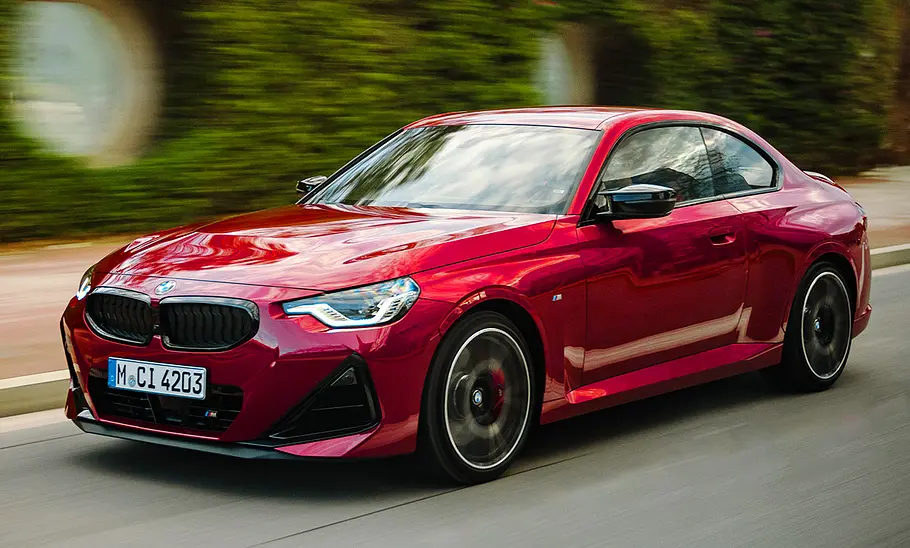 Das BMW M240i xDrive Facelift (2024) fährt auf einer Straße, von vorne links fotografiert.