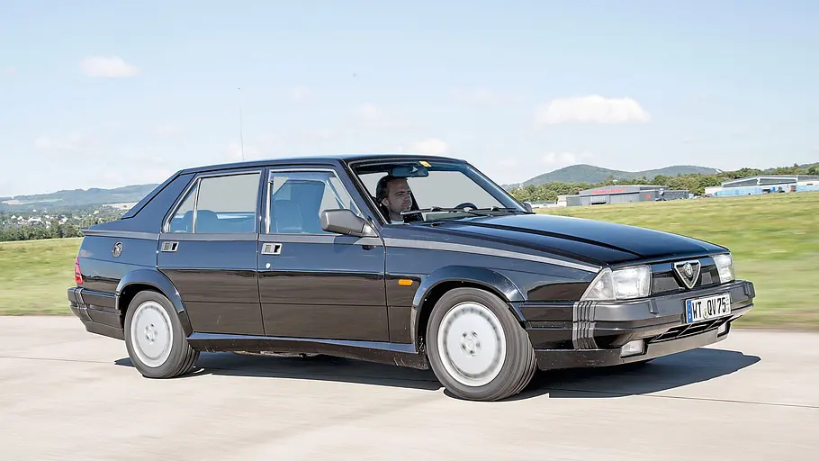 Alfa Romeo 75 3.0 QV fahrend von schräg vorne fotografiert. 