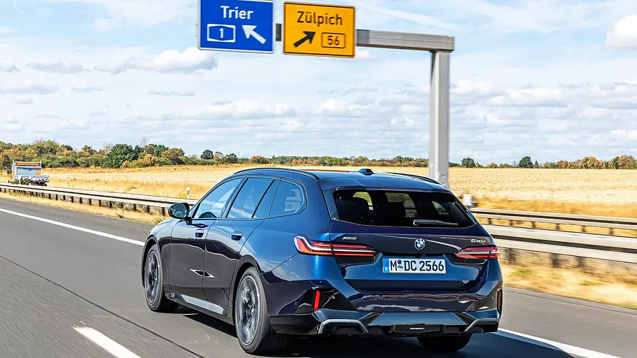 Dunkelblauer BMW 540d xDrive Touring in der Fahraufnahme schräg von hinten auf der Autobahn