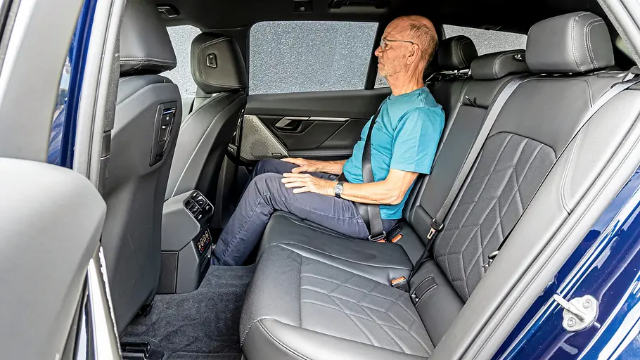 Ein Mann sitzt entspannt im Fond des BMW 540d xDrive Touring auf der schwarzen Lederrückbank