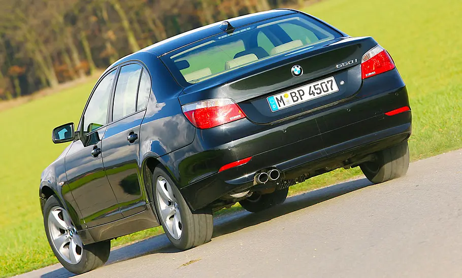 Der BMW 550i fahrend von schräg hinten fotografiert.