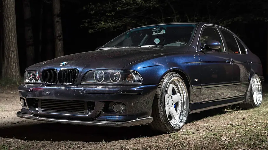 Platz 5: KMS BMW 5er (E39) mit 2JZ-Motor Getunter BMW 5er E39 mit Toyota-Motor im Wald, fotografiert von schräg vorne.