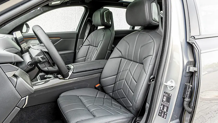 BMW 740 xDrive Einzeltest 7er Facelift Durch die offene Fahrertür des BMW 7er Facelift sind schwarze Ledersitze, Lenkrad und Mittelkonsole im Innenraum zu sehen.