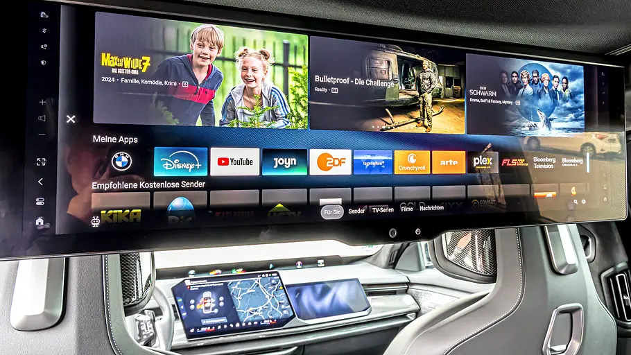 BMW 740 xDrive Einzeltest 7er Facelift Ein großer Bildschirm im BMW 7er zeigt Streaming-Apps und Filmangebote. Darunter sind Vordersitze und Armaturenbrett sichtbar.
