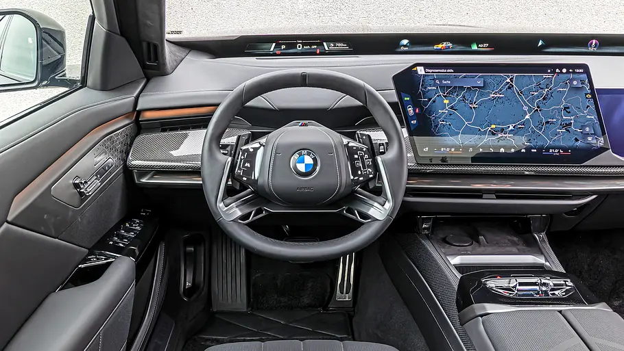BMW 740 xDrive Einzeltest 7er Facelift Das BMW 7er Facelift Cockpit zeigt ein Lenkrad, eine breite digitale Anzeige und einen großen Navigationsbildschirm über der Mittelkonsole.