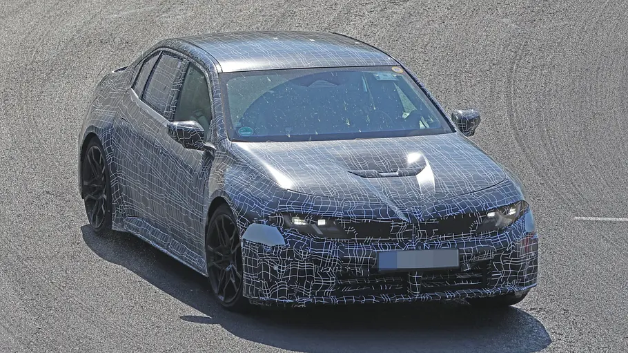 BMW i3 M (2027) Der BMW i3 M fährt als Erlkönig auf einer Rennstrecke, von vorne fotografiert.