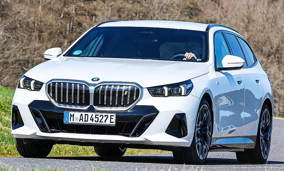 Der BMW i5 xDrive40 Touring fahrend von schräg vorne fotografiert.