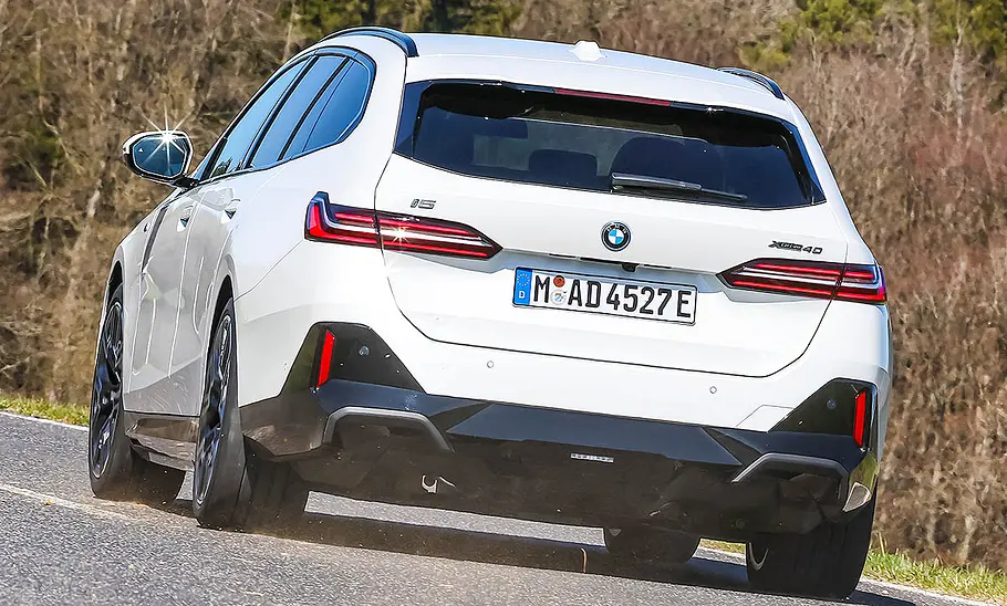 Der BMW i5 xDrive40 Touring fahrend von schräg hinten fotografiert.