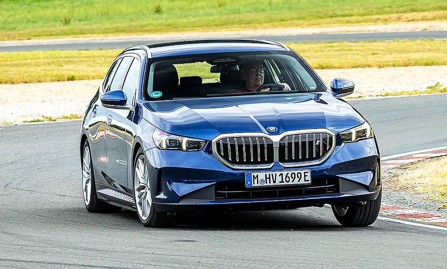 Blick von schräg vorne auf den BMW i5 Touring, der über eine Rennstrecke fährt.