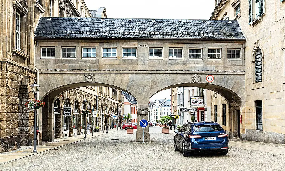 BMW i5 Touring Blick von hinten auf den BMW i5 Touring, der unter einem Torbogen entlang fährt.