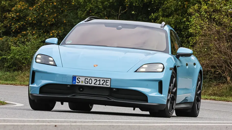 Porsche Taycan Sport Turismo Der Porsche Taycan Sport Turismo fährt durch eine Rechtskurve, von vorne fotografiert.