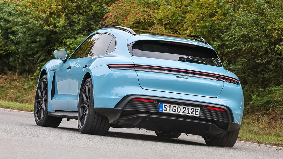 Porsche Taycan Sport Turismo Der Porsche Taycan Sport Turismo fährt durch eine Linkskurve, von hinten fotografiert.