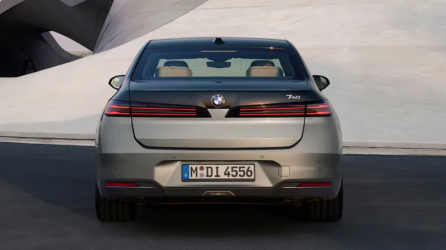 BMW i7 Facelift Der BMW i7 steht vor einer amorphen Beton-Fassade, von hinten fotografiert.
