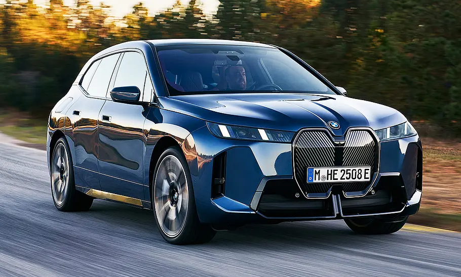 BMW iX Facelift (2025) Blick von schräg vorne auf das fahrende BMW iX Facelift (2025).