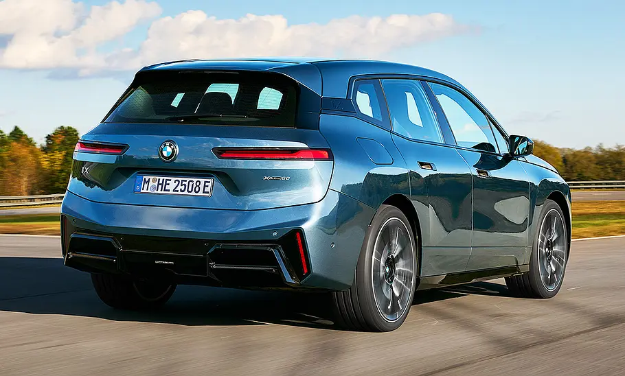 BMW iX Facelift (2025) Blick von schräg hinten auf das fahrende BMW iX Facelift (2025).