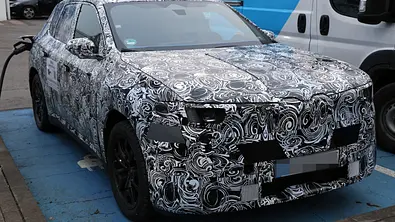 Als Erlkönig erwischt: Der BMW iX1 steht an einer Ladesäule, fotografiert von schräg vorne. - Foto: SH Proshots