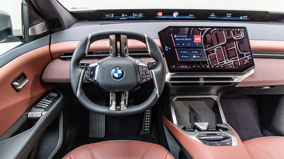 Das BMW iX3hat ein kantiges Lenkrad, einen großen Navigationsbildschirm und eine rotbraune Innenausstattung.