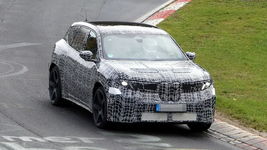 BMW iX3 M (2027) Der BMW iX3 (2027) fährt als Erlkönig auf der Nürburgring-Nordschleife, von vorne fotografiert.