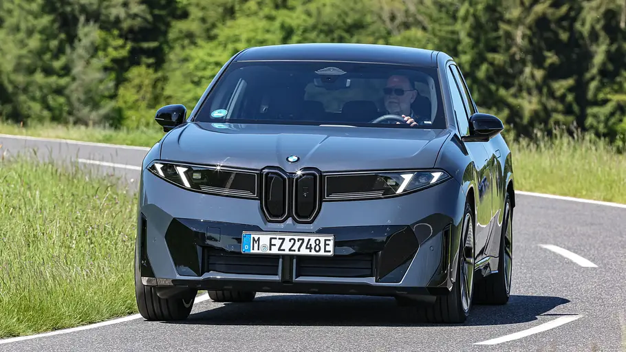 BMW iX3 Der BMW iX3 fährt durch eine Kurve, von vorne fotografiert.