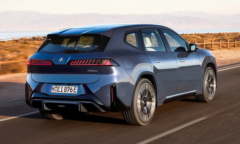 Der BMW iX3 (2026) fahrend von schräg hinten fotografiert.